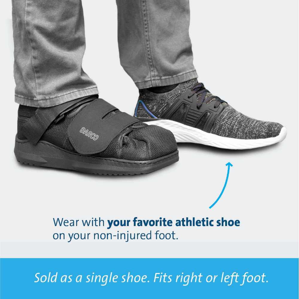 Black orthopedic shoe worn with a gray athletic shoe on a light gray background